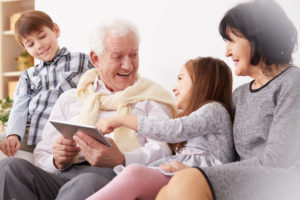 older couple with two grandchildren looking at a tablet