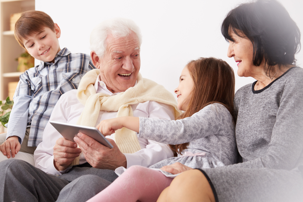older couple with two grandchildren looking at a tablet