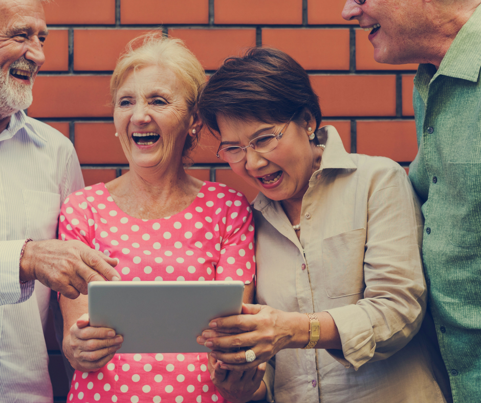 four people looking at a tablet and laughing