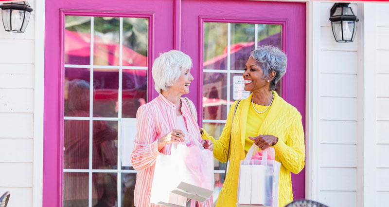 two women shopping in front of a pink door