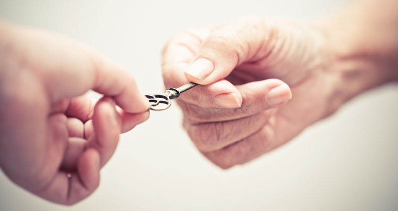 close up of one person handing a key to another person