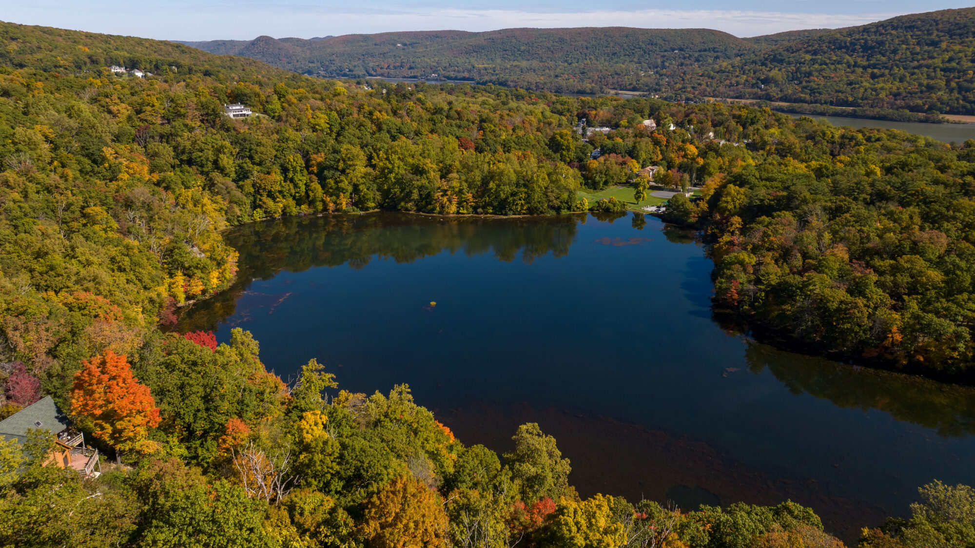 An aerial of a lake in upstate New York during the colorful fall foliage on a sunny day