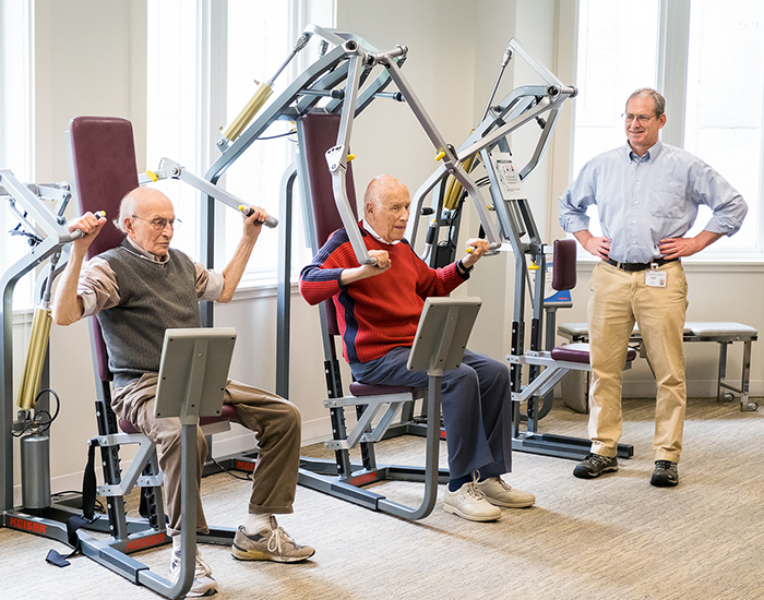 Two male residents exercising with staff supervision