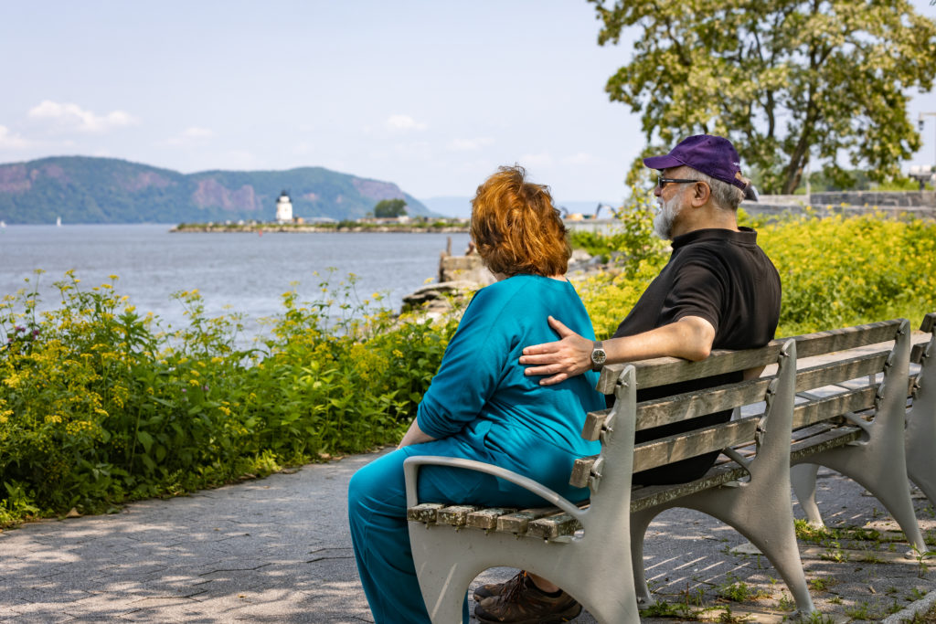 Woman and Man sitting on bench looking at scenic views from Kendal on the Hudson Walk Town