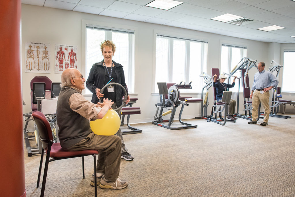 Resident working out with staff looking on