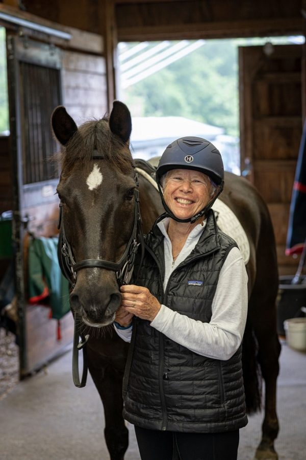 Smiling woman with her horse in a stable