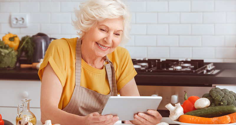 Grandparent looking at tablet in kitchen