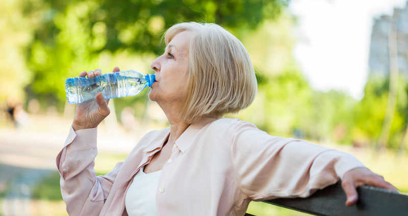 Woman drinking water to stay hydrated in summer heat