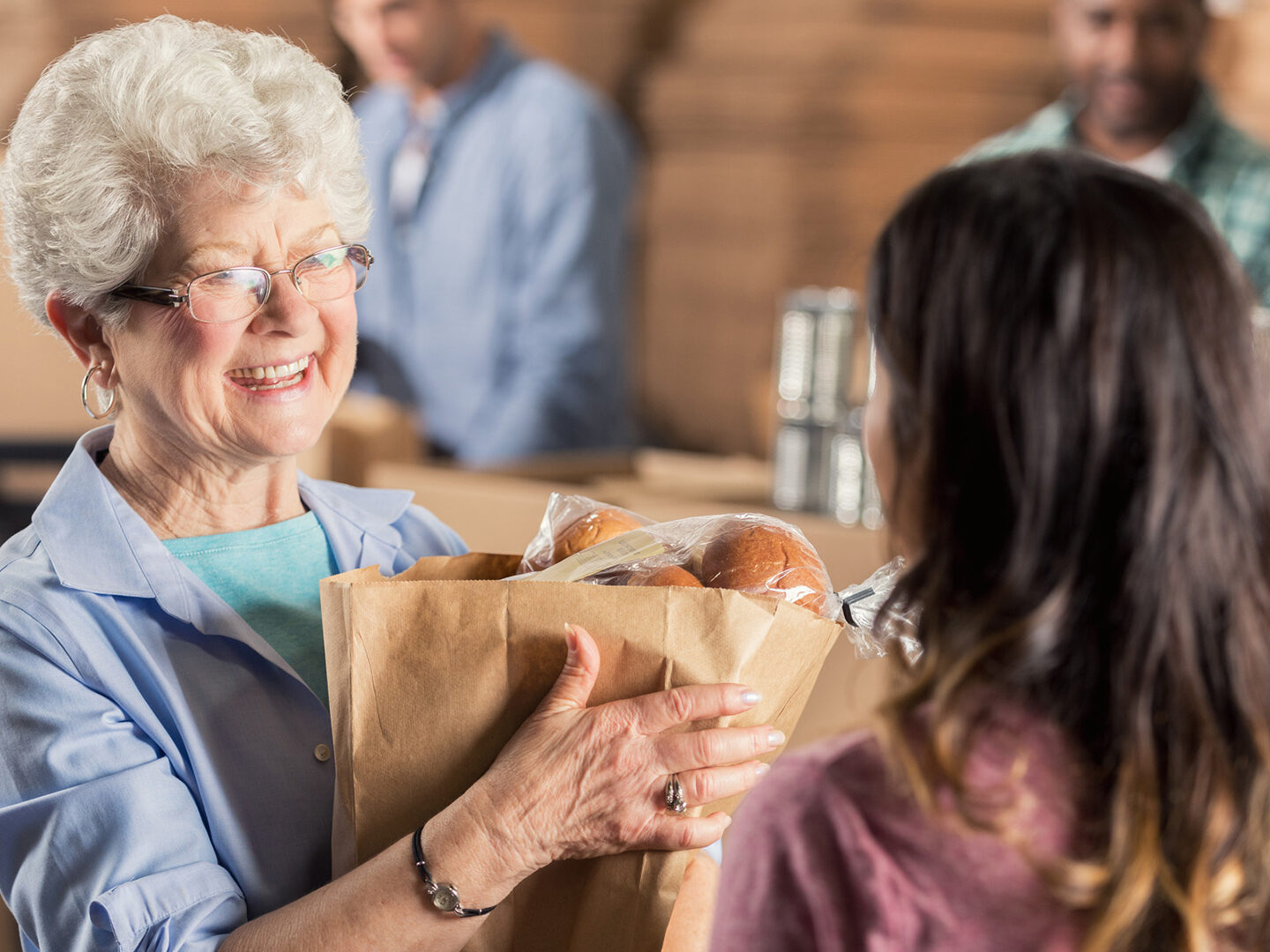 A beautiful senior woman donates a bag of groceries during a community food drive.