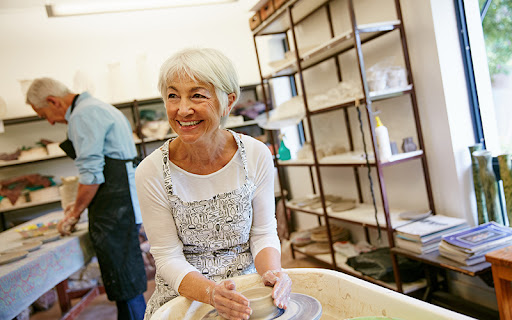 senior woman in a pottery class turning a vase