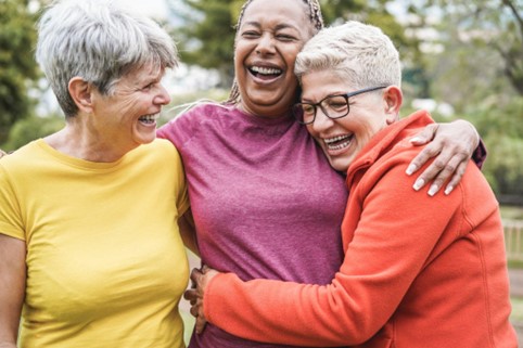 group of senior women laughing and hugging outside