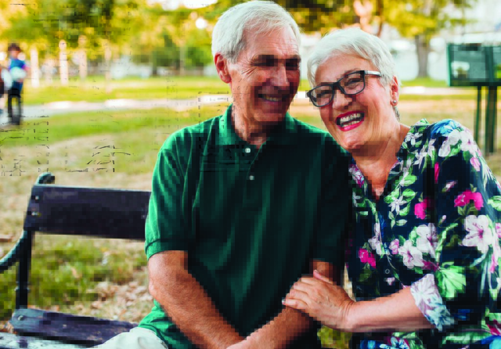 senior couple smiling on a park bench