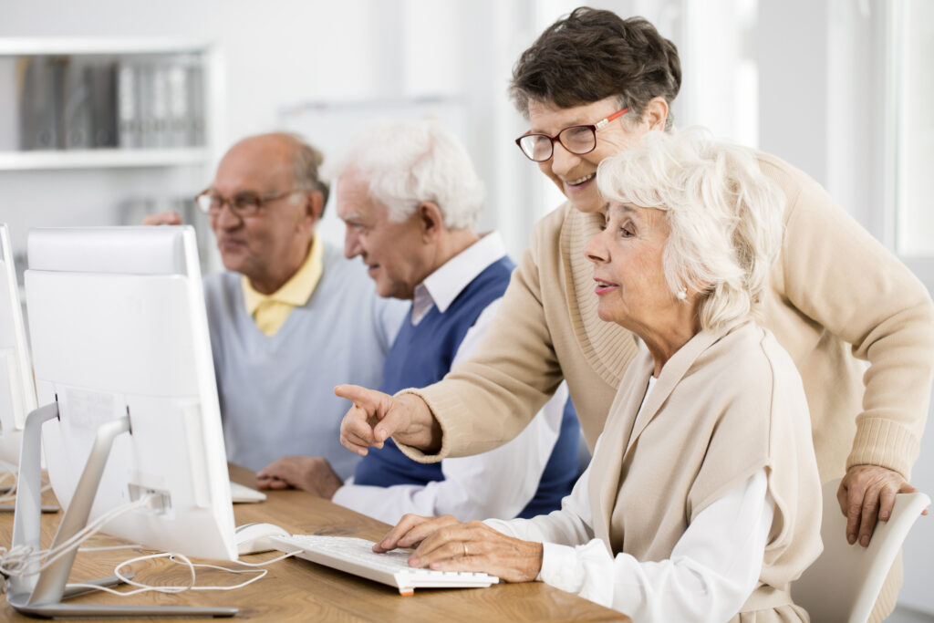 Elder lady with glasses helping her friend with computer issue
