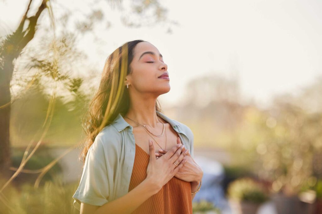 young woman standing outside with her hands to her chest