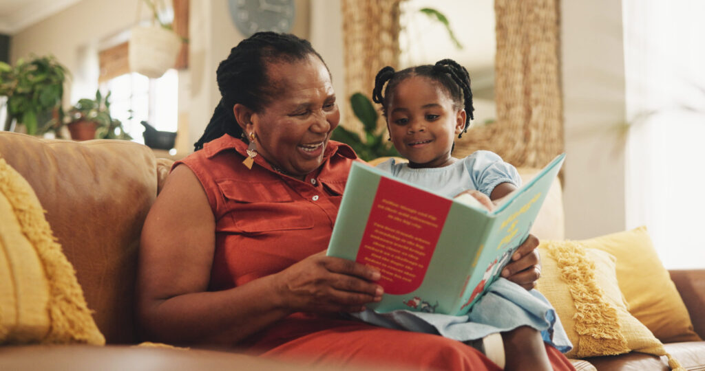 Grandmother reading book to her young granduaghter as grandparents day ideas at Kendal on Hudson.