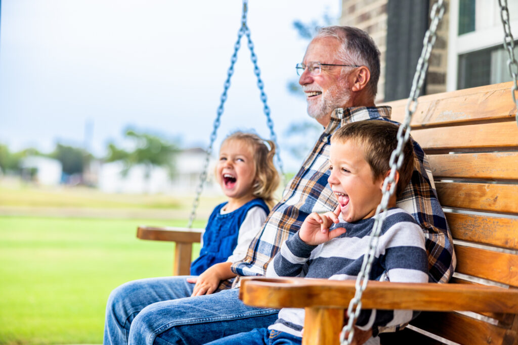 Grandparents day ideas: Grandfather with granddaughter and grandson sitting on bench swing at Kendal on Hudson.