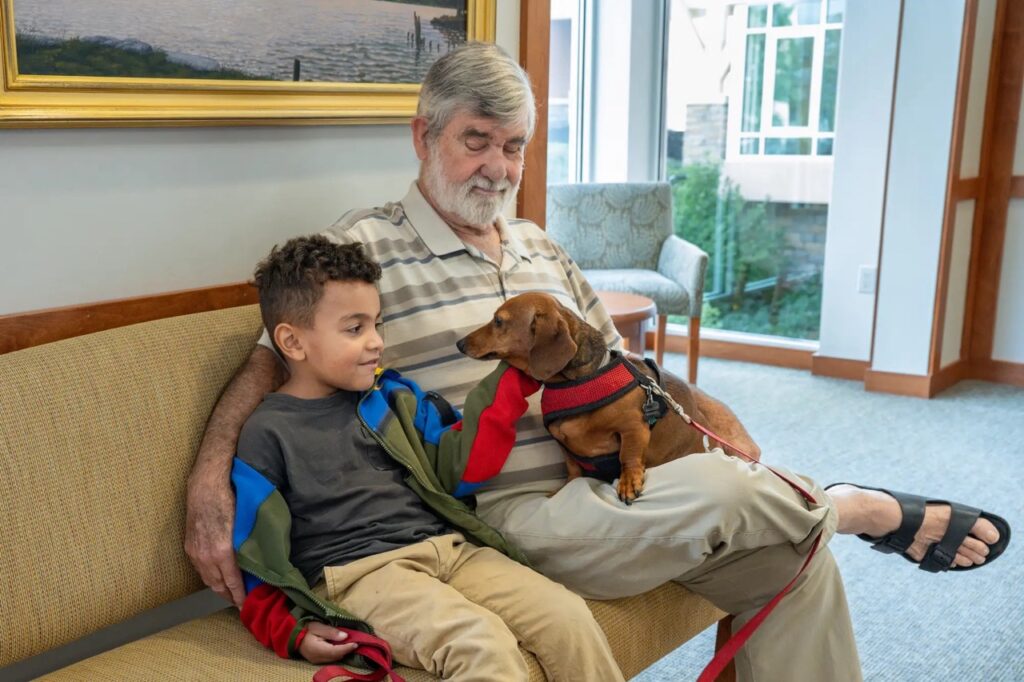 Resident of Kendal on Hudson and grandson sitting with dog